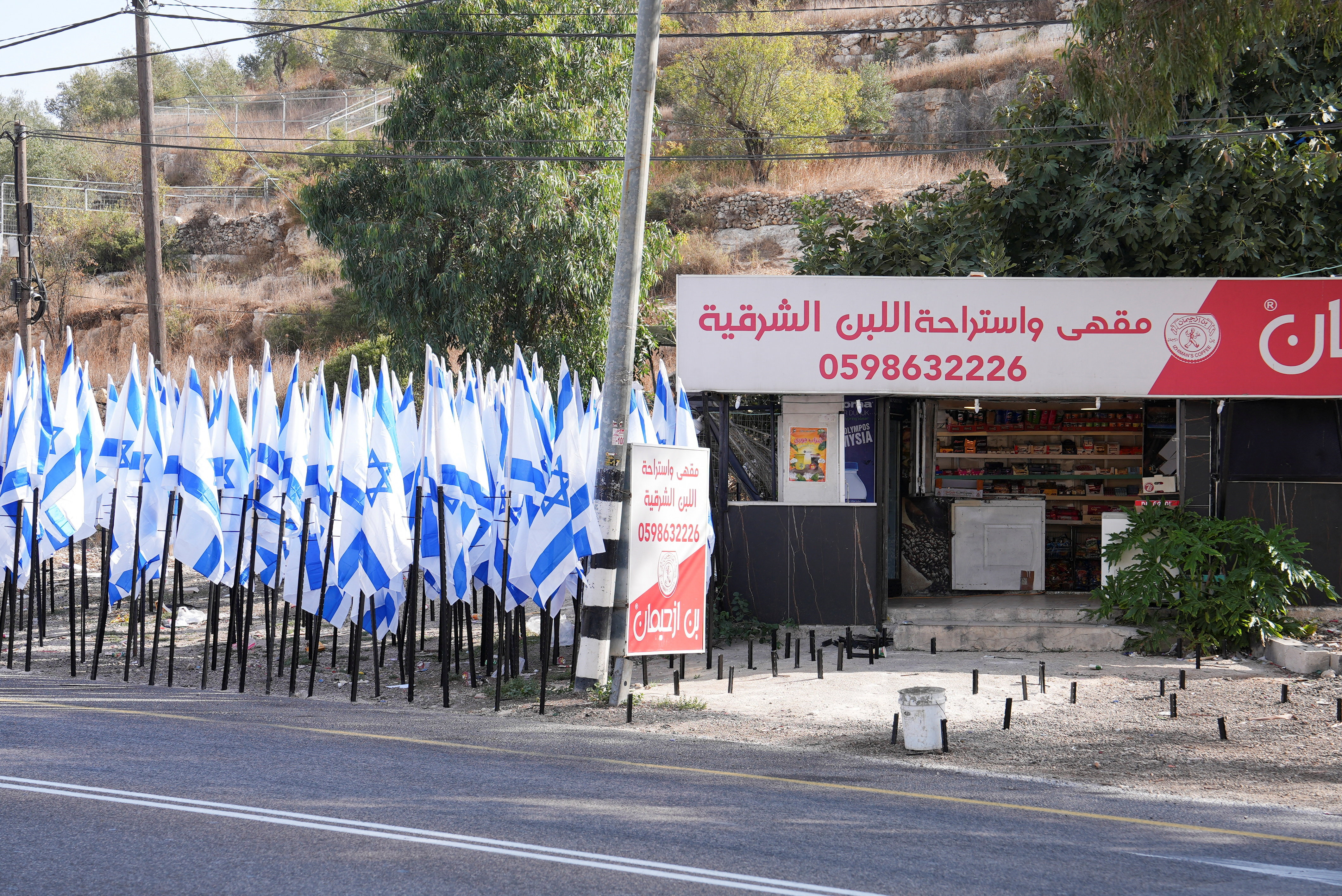 Colonos israelenses flanqueiam uma cafeteria palestina com dezenas de bandeiras israelenses
