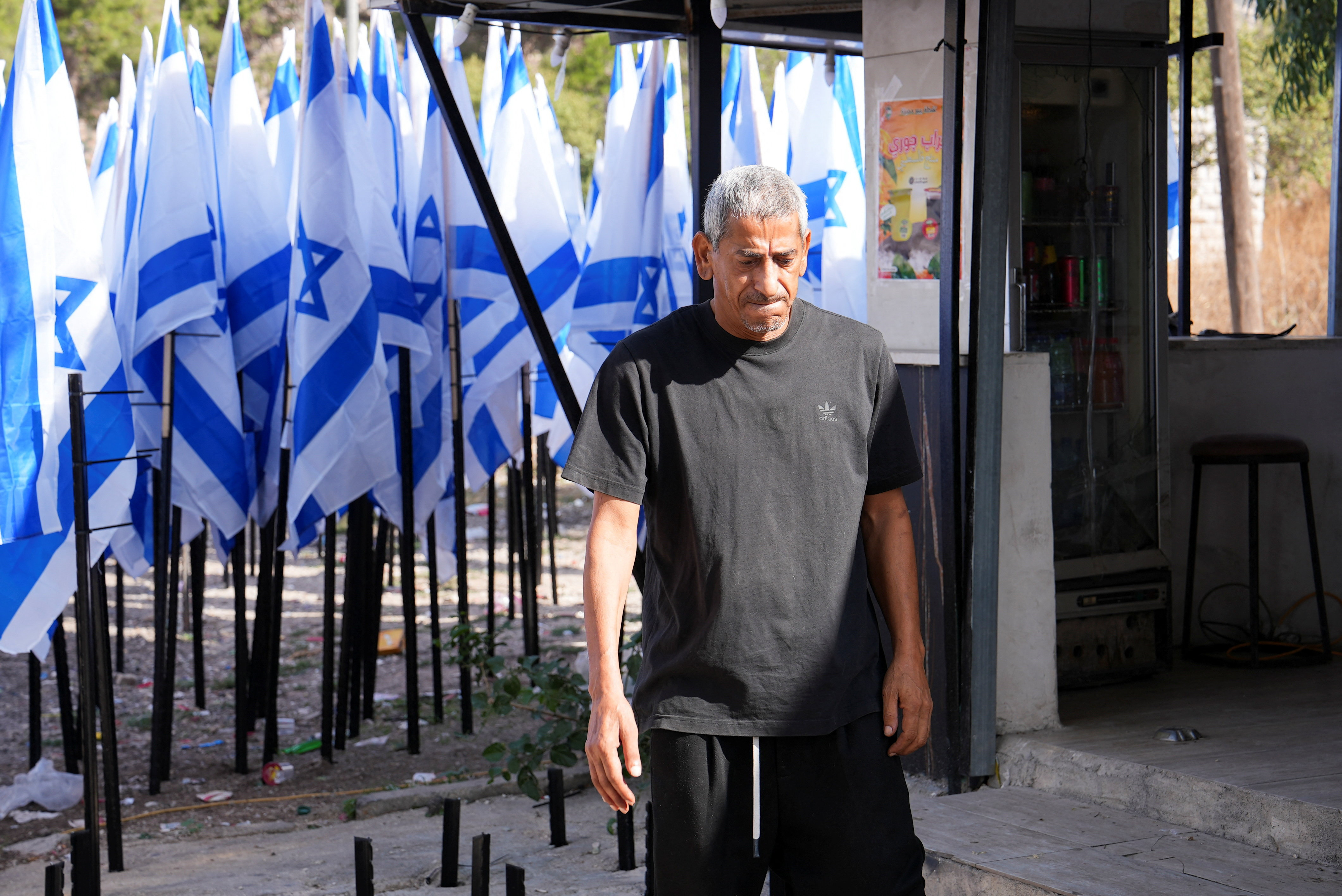 Colonos israelenses flanqueiam uma cafeteria palestina com dezenas de bandeiras israelenses