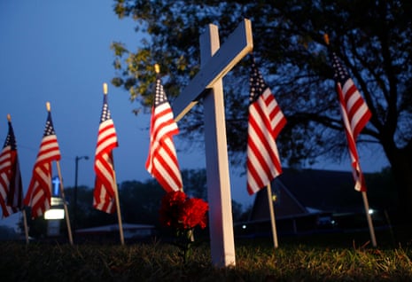 a cross stands at a memorial in front of US flags