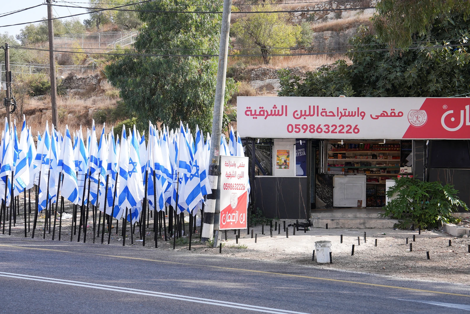 Colonos israelenses flanqueiam uma cafeteria palestina com dezenas de bandeiras israelenses
