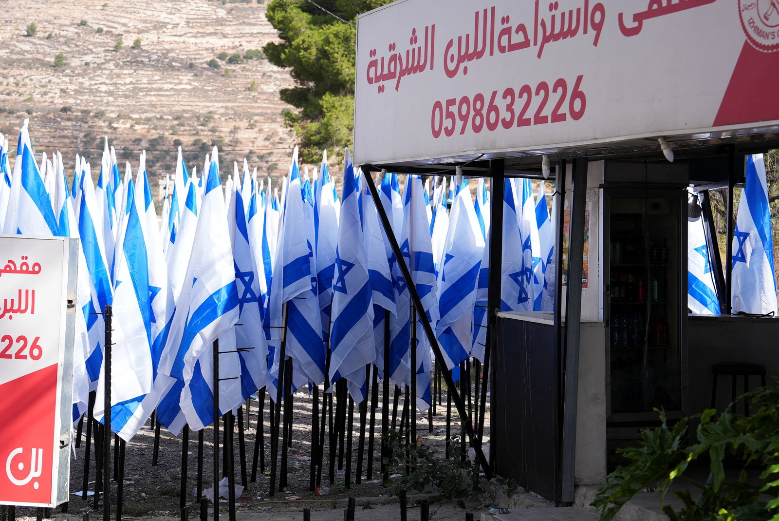 Colonos israelenses flanqueiam uma cafeteria palestina com dezenas de bandeiras israelenses